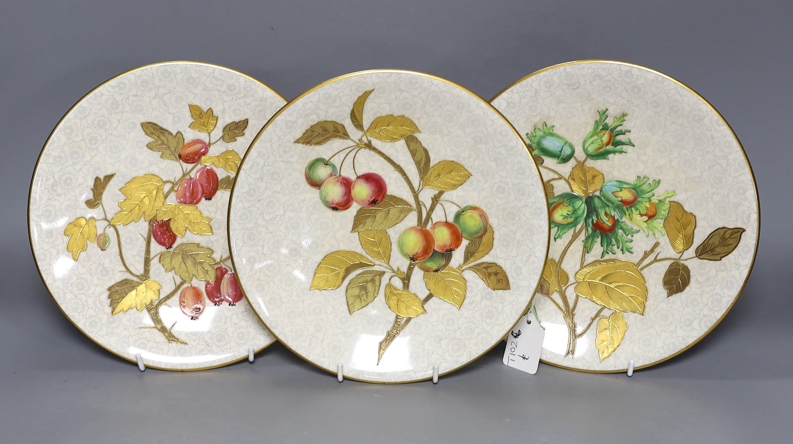 Three Royal Worcester Aesthetic period plates, with raised gilded and enamelled botanical decoration, on a floral ground, originally retailed by Gardner’s Strand, London. 23cm diameter.